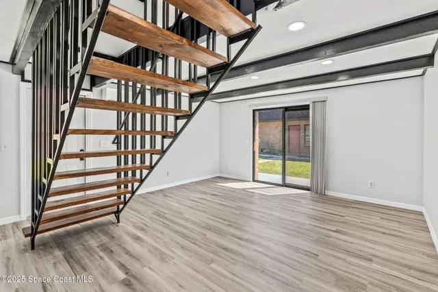 an empty room with wooden floor and stairs