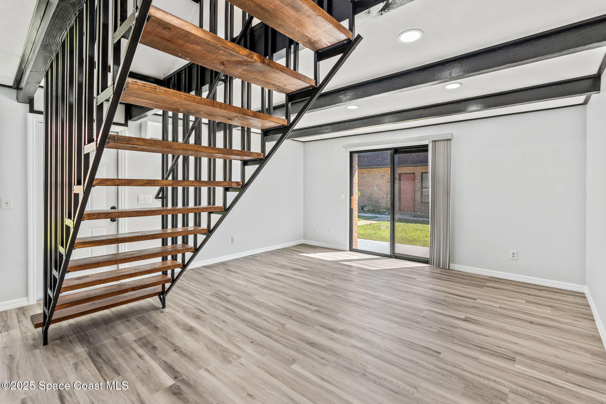 3316 Overlook Drive, Unit 62 Palm Bay, FL 32905 - Photo 8 of 23 an empty room with wooden floor and stairs