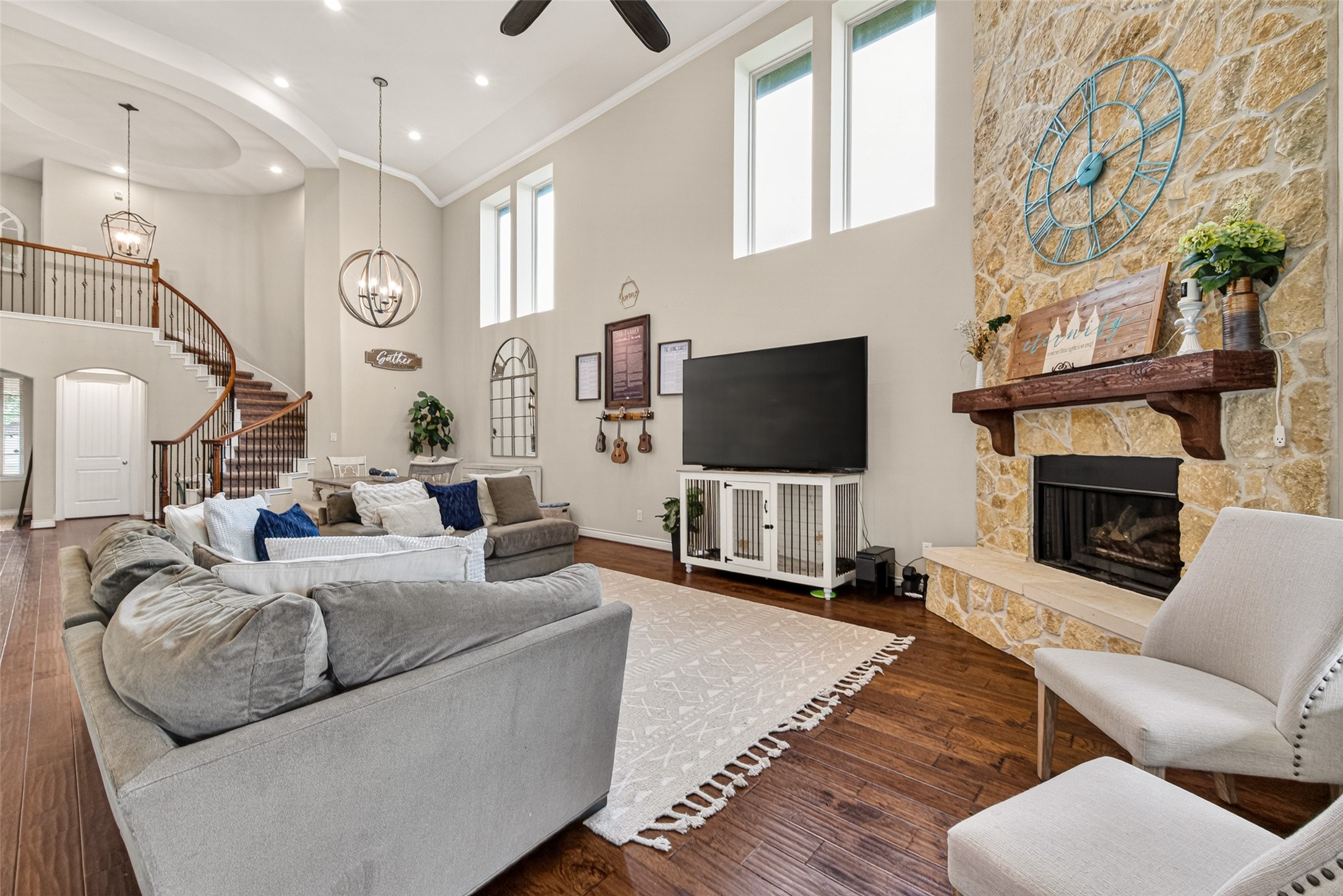 25611 Ellis Ridge Court Katy, TX 77494 - Photo 10 of 49 Spacious living room with high ceilings, featuring a curved staircase, stone fireplace, and large windows for natural light. The room includes a cozy seating area, modern decor, and hardwood floors, creating an inviting atmosphere.