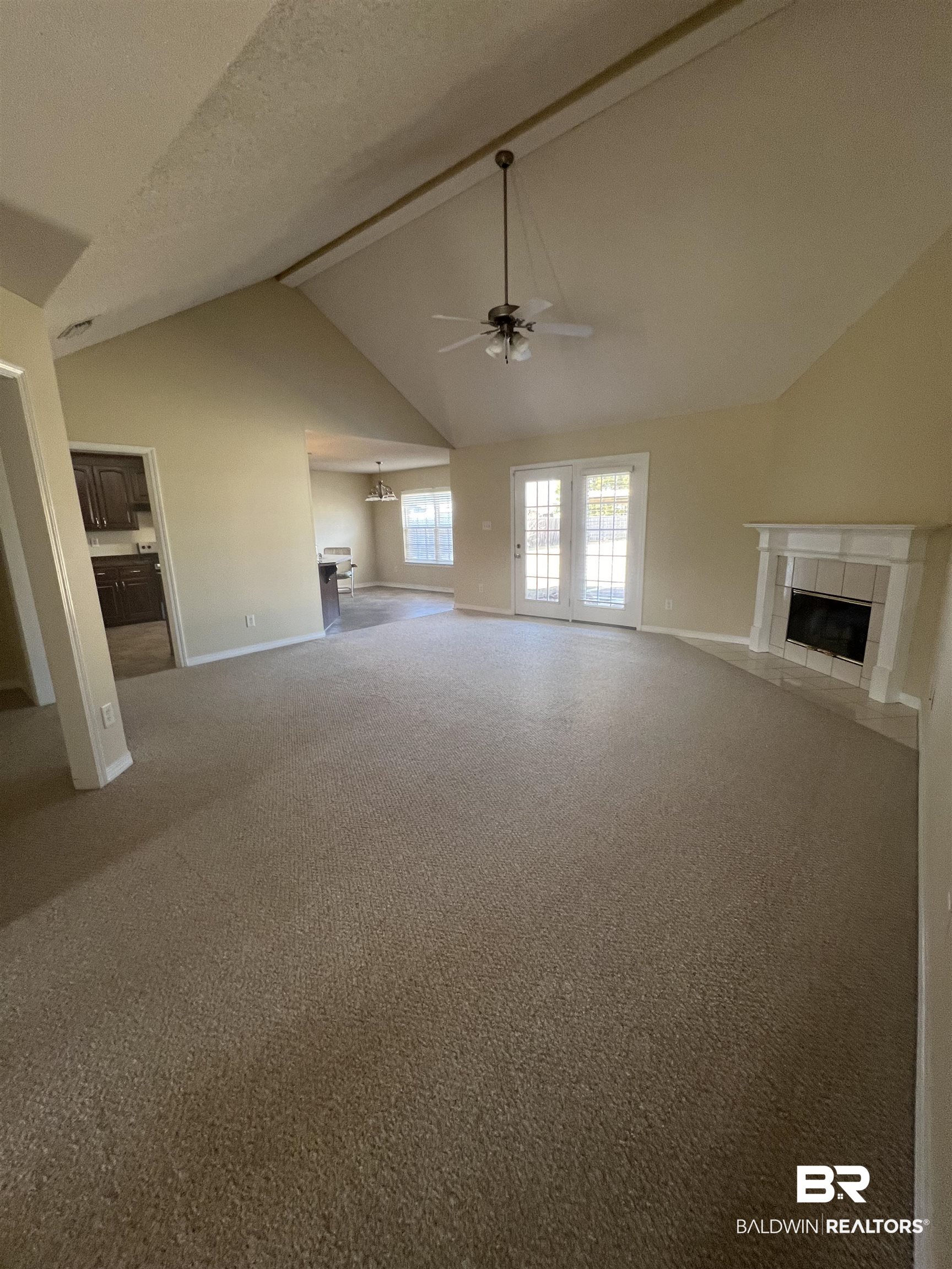 17793 Fancy Boulevard Foley, AL 36535 - Photo 3 of 34 Unfurnished living room with vaulted ceiling, carpet floors, a tiled fireplace, ceiling fan, and a textured ceiling