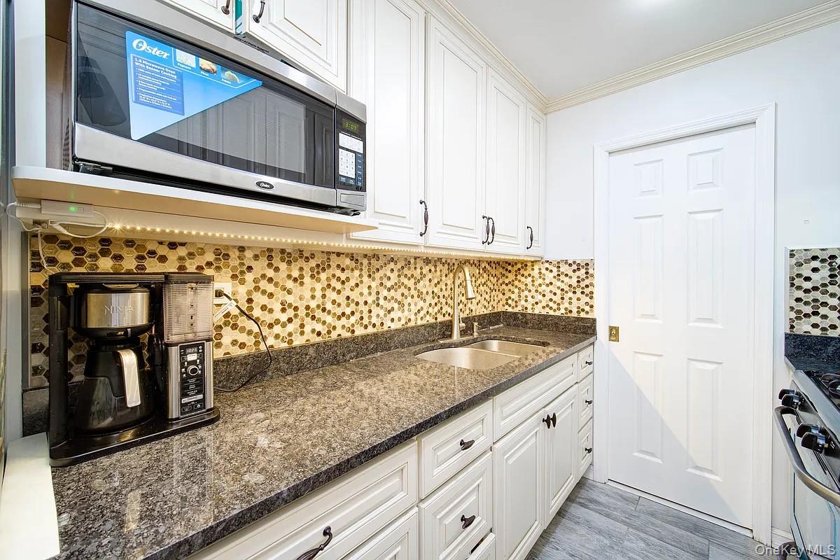 99-05 59th Avenue, Unit 2A Queens, NY 11368 - Photo 4 of 14 a kitchen with granite countertop white cabinets and sink