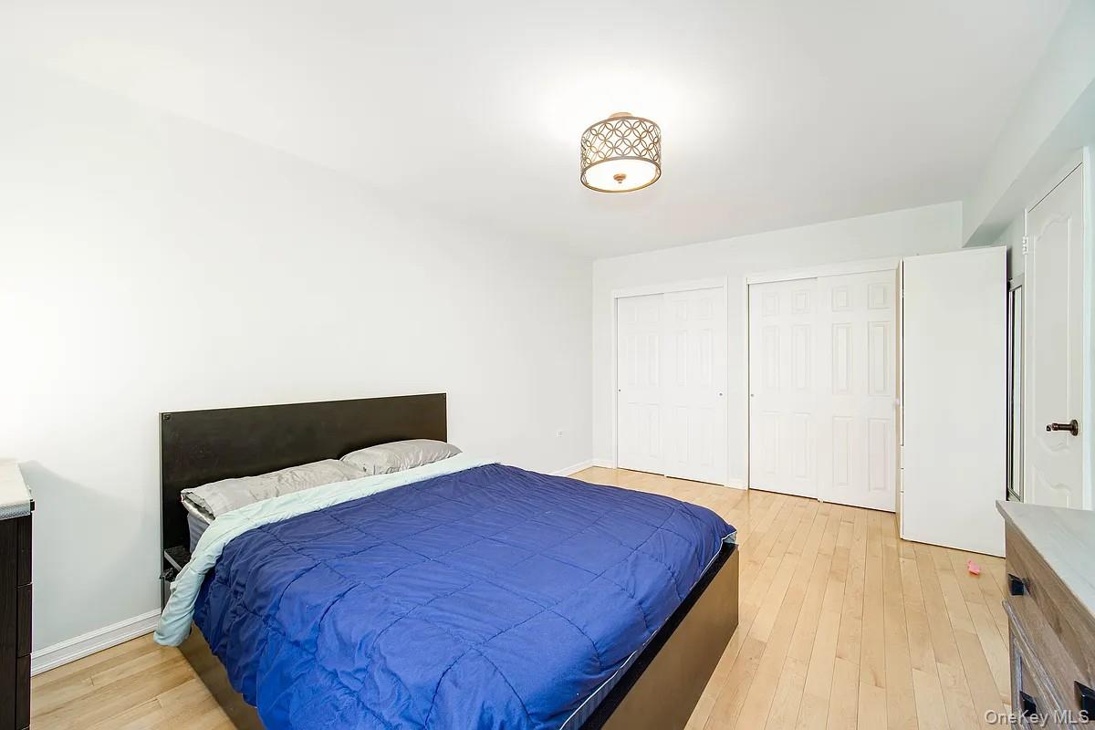 99-05 59th Avenue, Unit 2A Queens, NY 11368 - Photo 7 of 14 a bedroom with a bed and a wooden floor