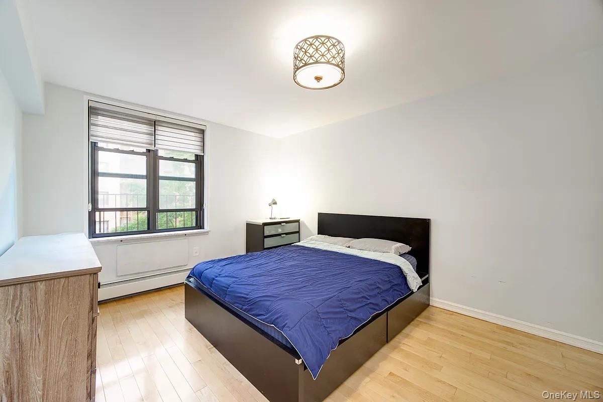 99-05 59th Avenue, Unit 2A Queens, NY 11368 - Photo 8 of 14 a bedroom with a bed and window