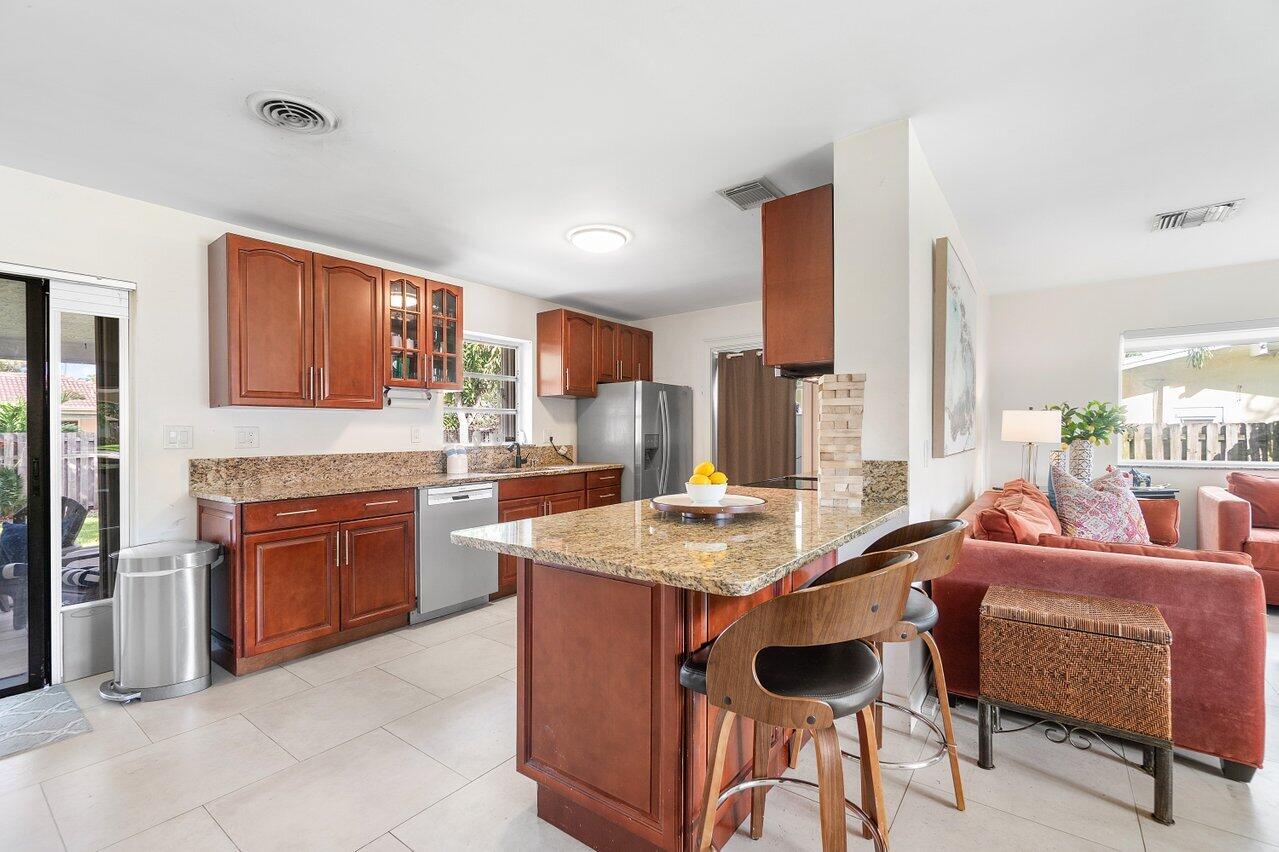 1069 West Camino Real Boca Raton, FL 33486 - Photo 4 of 21 a kitchen with stainless steel appliances granite countertop a stove top oven a sink a dining table and chairs