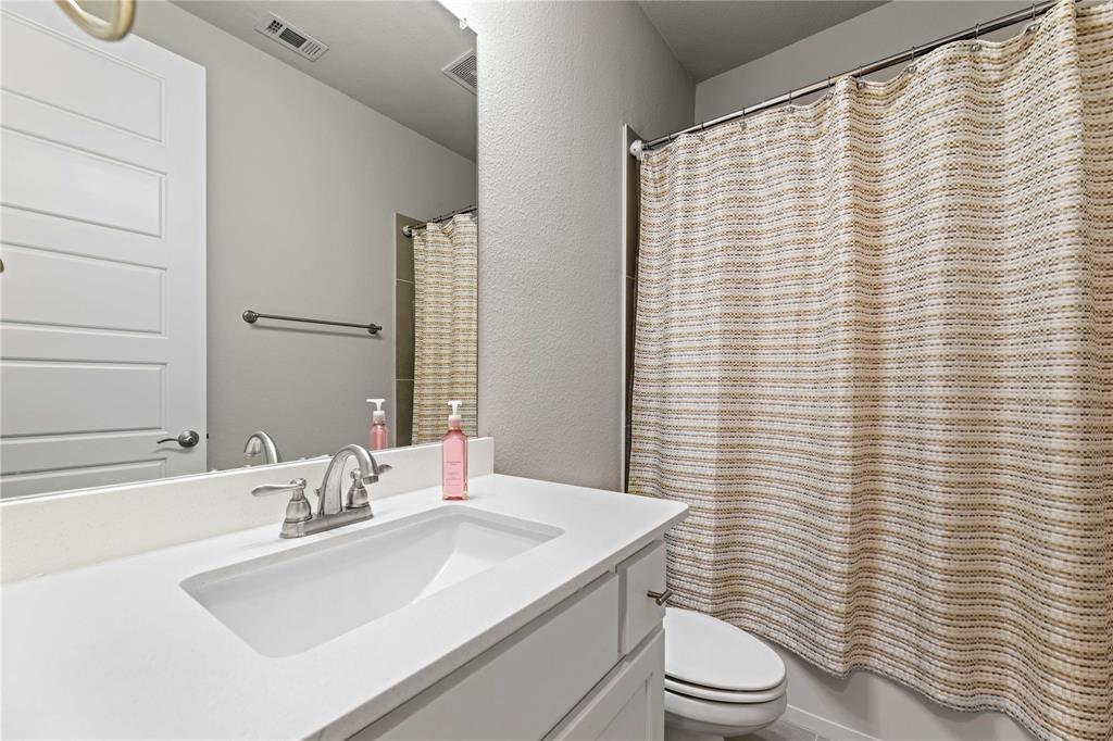 16541 Sweetgum Road Frisco, TX 75033 - Photo 14 of 28 Bathroom with vanity, a textured wall, and shower / bath combo with shower curtain