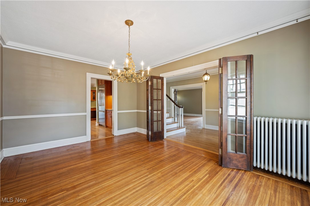 24510 Lake Road Bay Village, OH 44140 - Photo 17 of 45 Spare room with radiator, ornamental molding, light wood-type flooring, stairs, and a chandelier