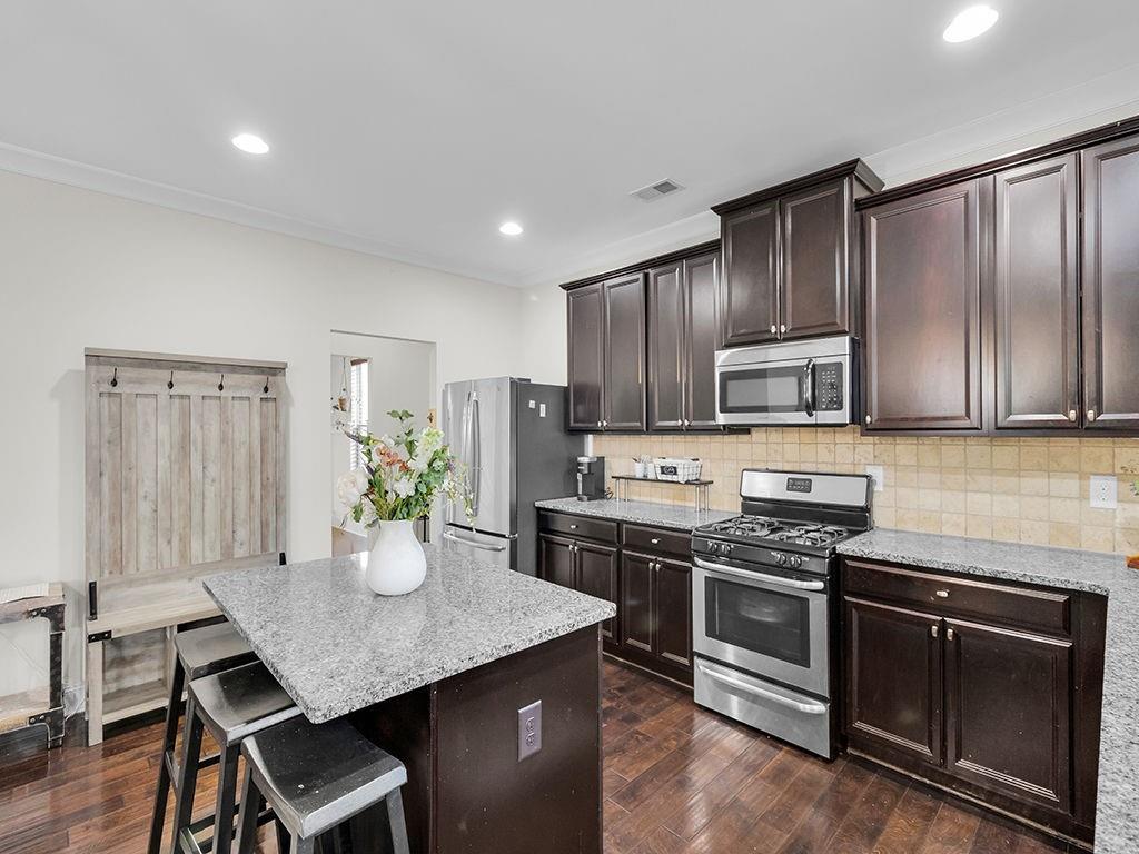 5110 Rialto Way Cumming, GA 30040 - Photo 13 of 50 a kitchen with stainless steel appliances kitchen island granite countertop a stove a sink a refrigerator and cabinets