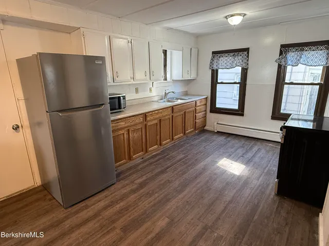 a kitchen with wooden floors white cabinets and stainless steel appliances
