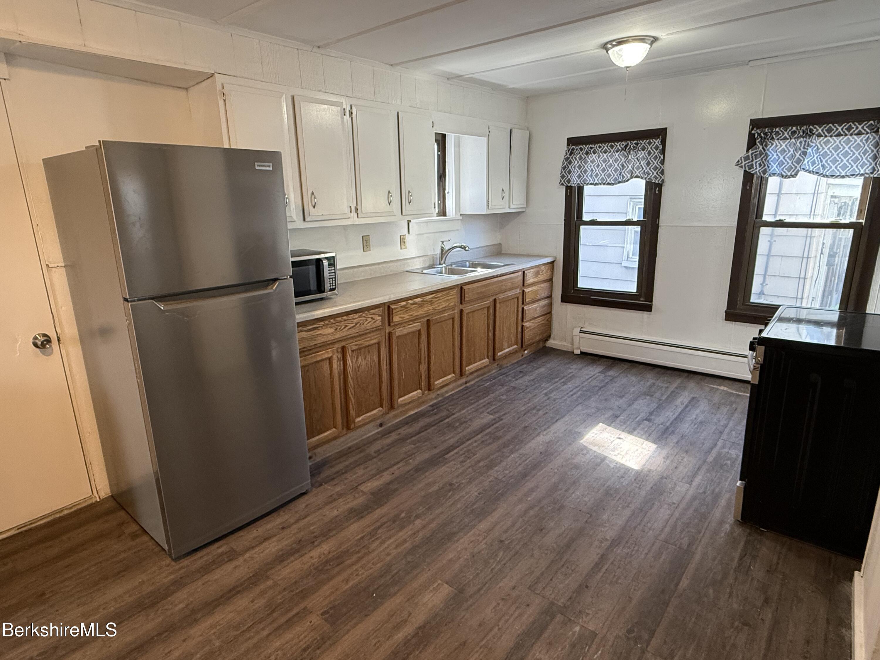 a kitchen with wooden floors white cabinets and stainless steel appliances