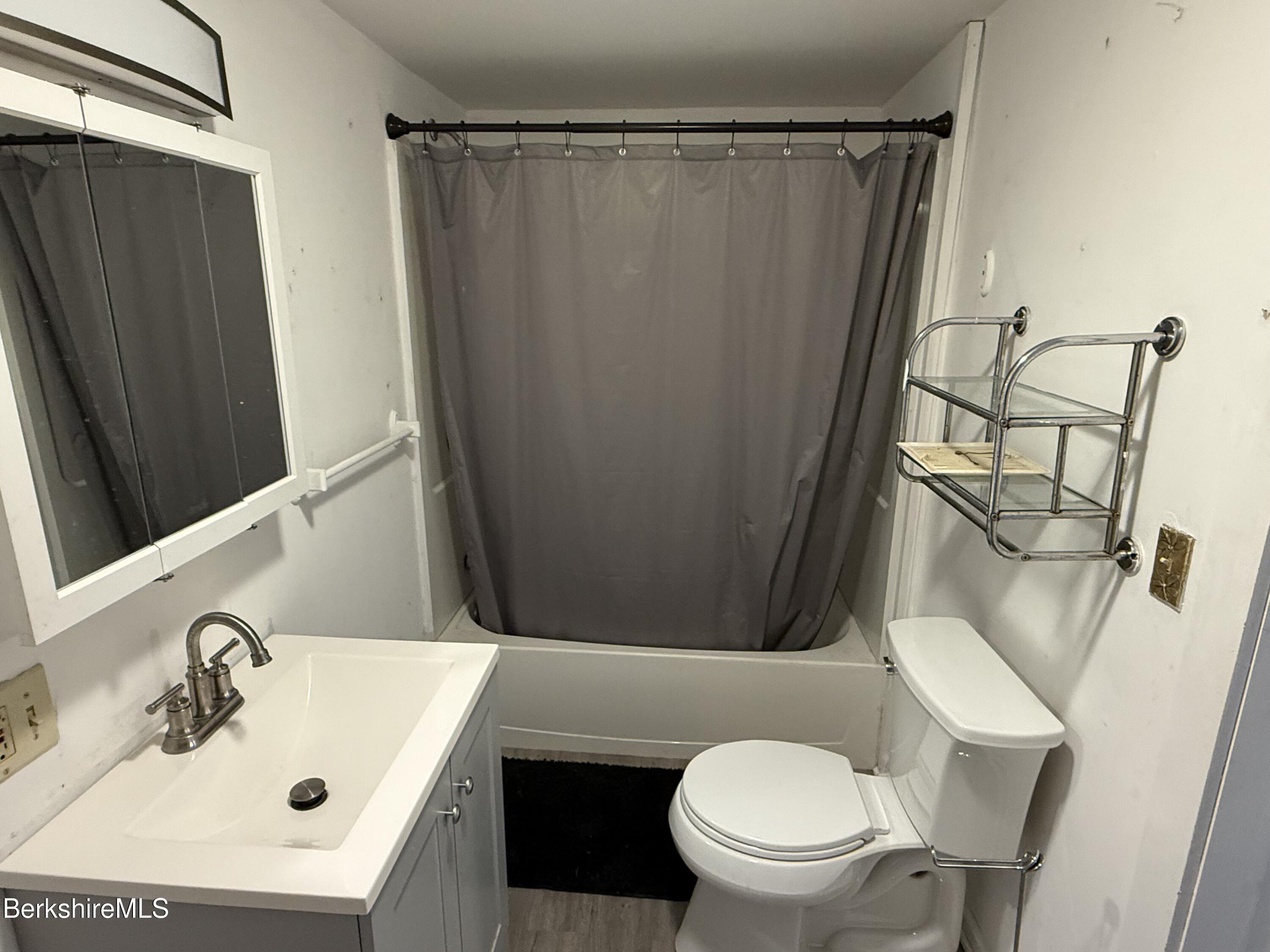 130 Commercial Street, Unit 1 Adams, MA 01220 - Photo 2 of 7 a bathroom with a sink a toilet a mirror and shower curtain