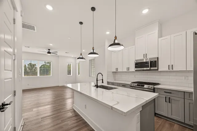 a kitchen with stainless steel appliances a sink a stove a microwave and wooden floor