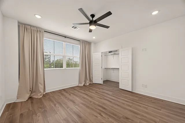a view of empty room with wooden floor and ceiling fan
