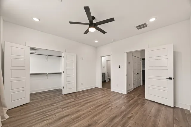 a view of an empty room with wooden floor and window