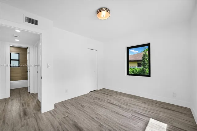 a view of an empty room with wooden floor and a window