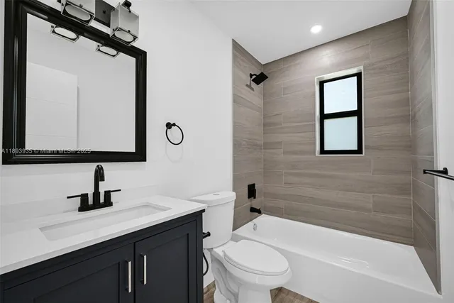 a bathroom with a toilet a sink a mirror a bathtub and vanity