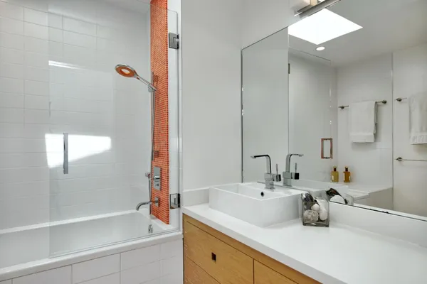 a bathroom with a sink and mirror with bathtub