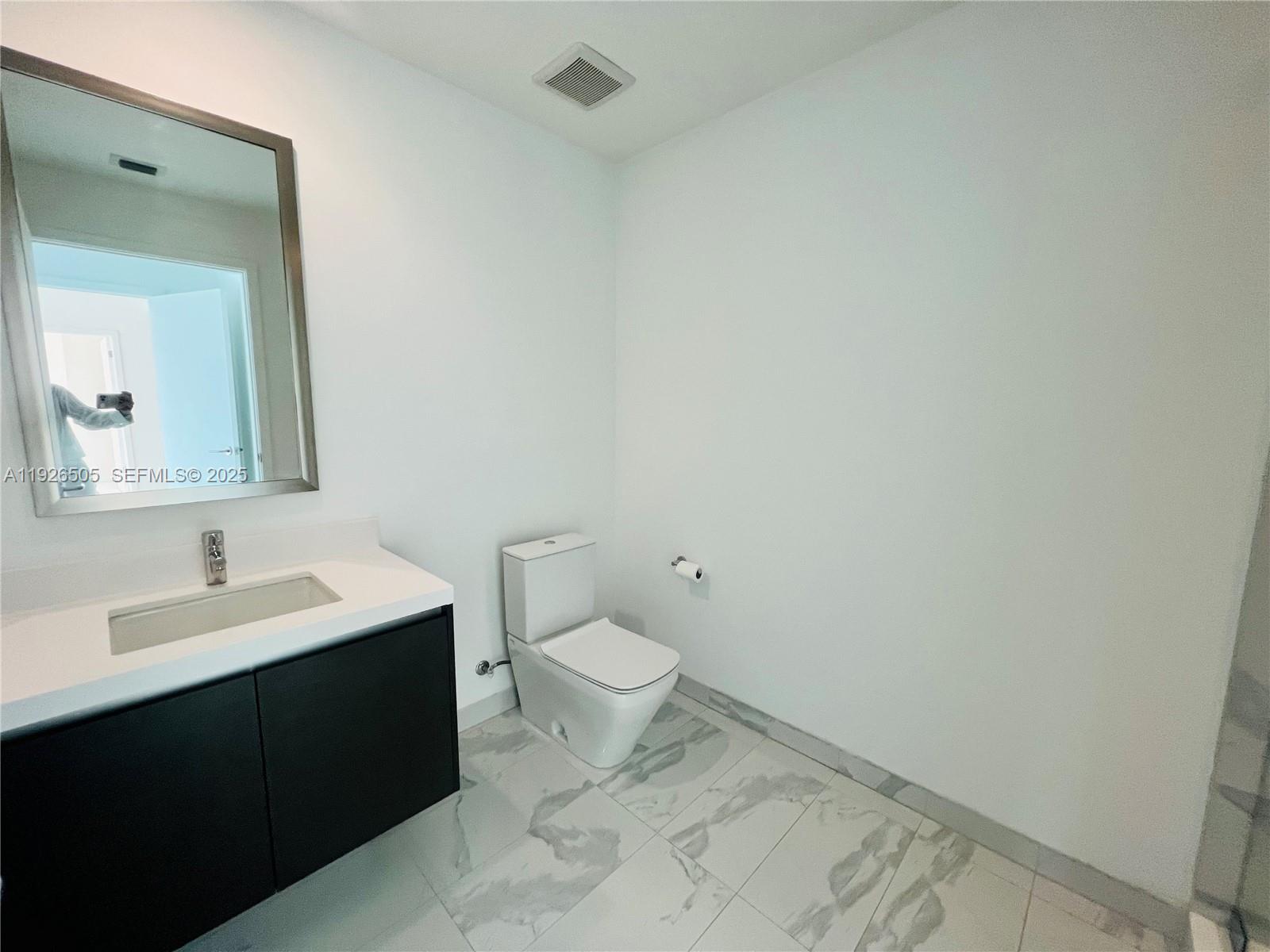 851 Northeast 1st Avenue, Unit 2808 Miami, FL 33132 - Photo 22 of 86 a bathroom with a toilet a sink and mirror
