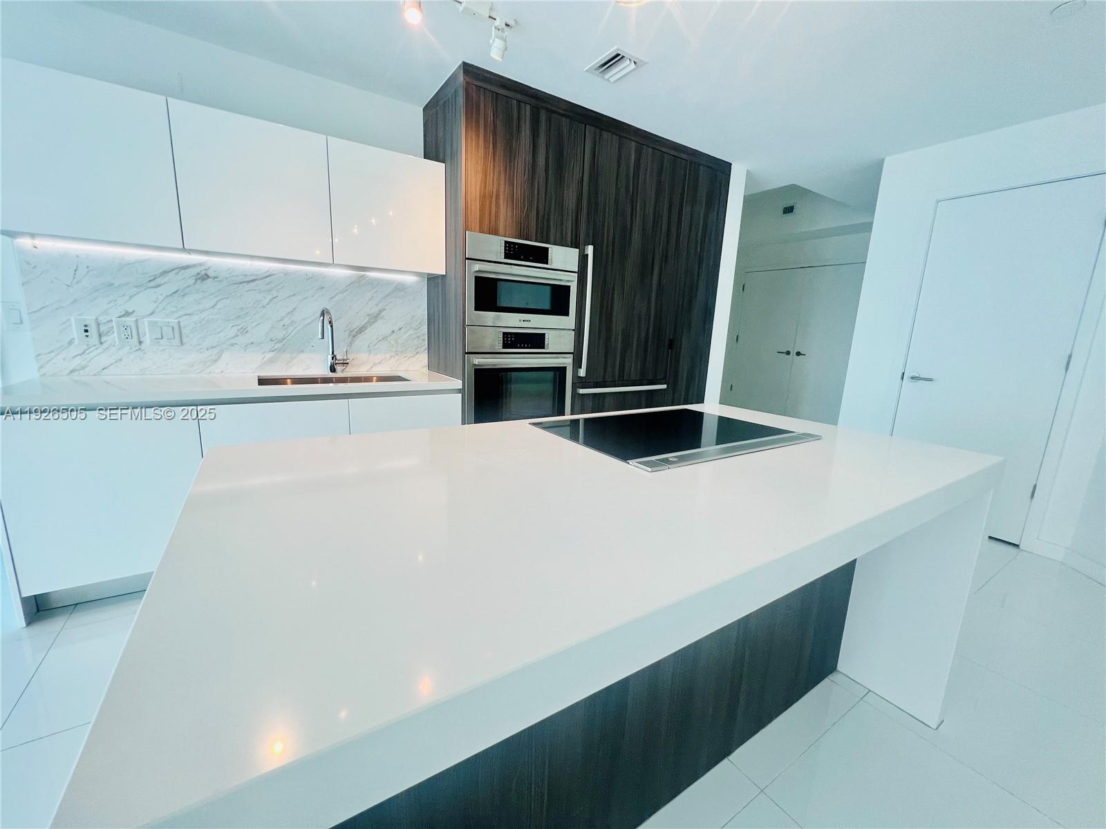 851 Northeast 1st Avenue, Unit 2808 Miami, FL 33132 - Photo 29 of 86 a kitchen with kitchen island a sink a stove and refrigerator