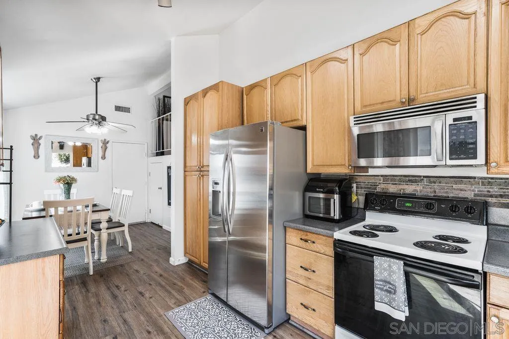 8659 Cordial Road El Cajon, CA 92021 - Photo 9 of 16 a kitchen with stainless steel appliances a stove a refrigerator and a dining table