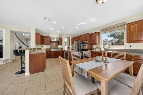 a living room with stainless steel appliances kitchen island granite countertop a table chairs and a refrigerator