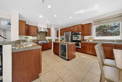 a kitchen with stainless steel appliances granite countertop a stove top oven a sink dishwasher a dining table and chairs with wooden floor