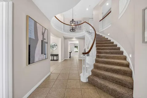 a view of staircase with white walls and chandelier