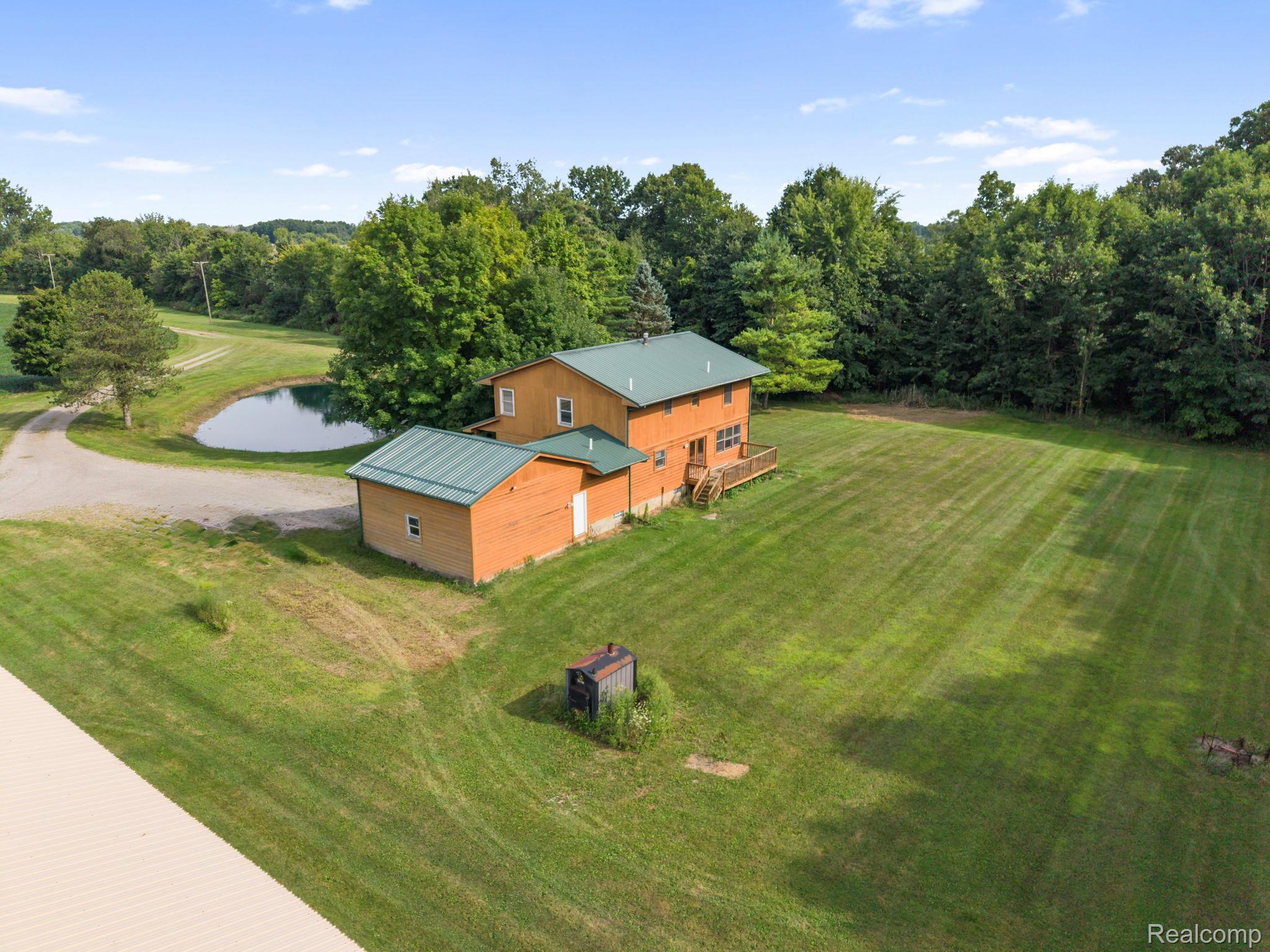 76565 McFadden Road Armada, MI 48005 - Photo 69 of 95 Wood-sided residence with green metal roofing, an attached garage, and a rear deck