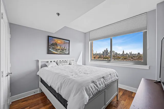 a bedroom with a bed painting on wall and a large window