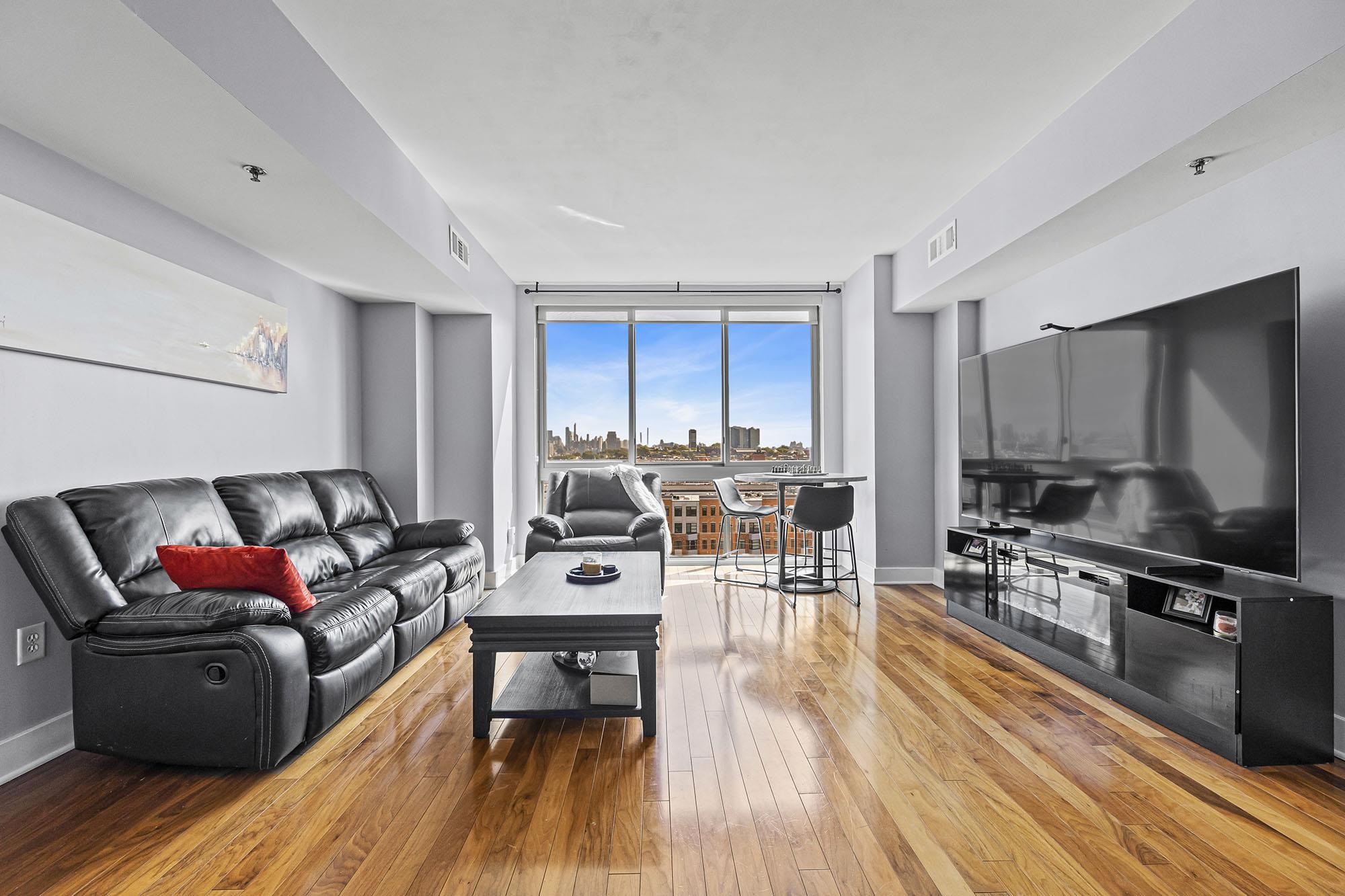800 Jackson Street, Unit PH7 Hoboken, NJ 07030 - Photo 2 of 22 a living room with furniture a flat screen tv and wooden floor