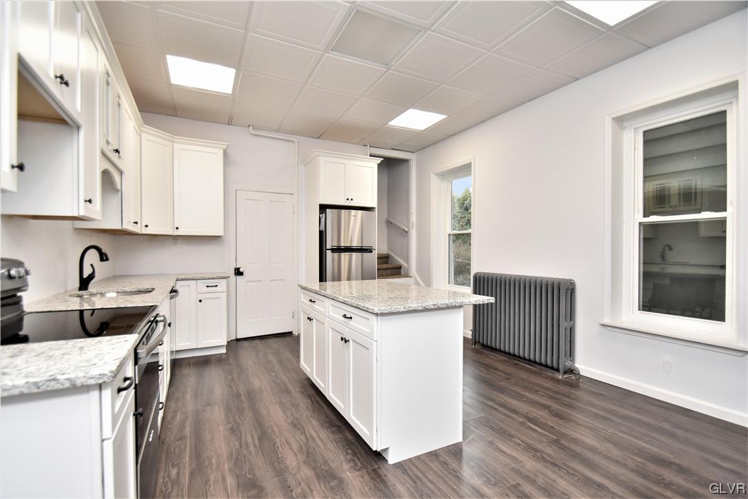 28 South 5th Street Emmaus, PA 18049 - Photo 10 of 23 a kitchen with granite countertop a stove top oven a sink dishwasher and white cabinets with wooden floor