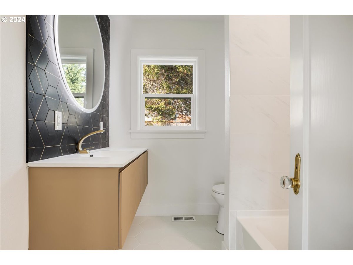 2639 North Sumner Street Portland, OR 97217 - Photo 22 of 46 a bathroom with a toilet a sink a mirror and a window