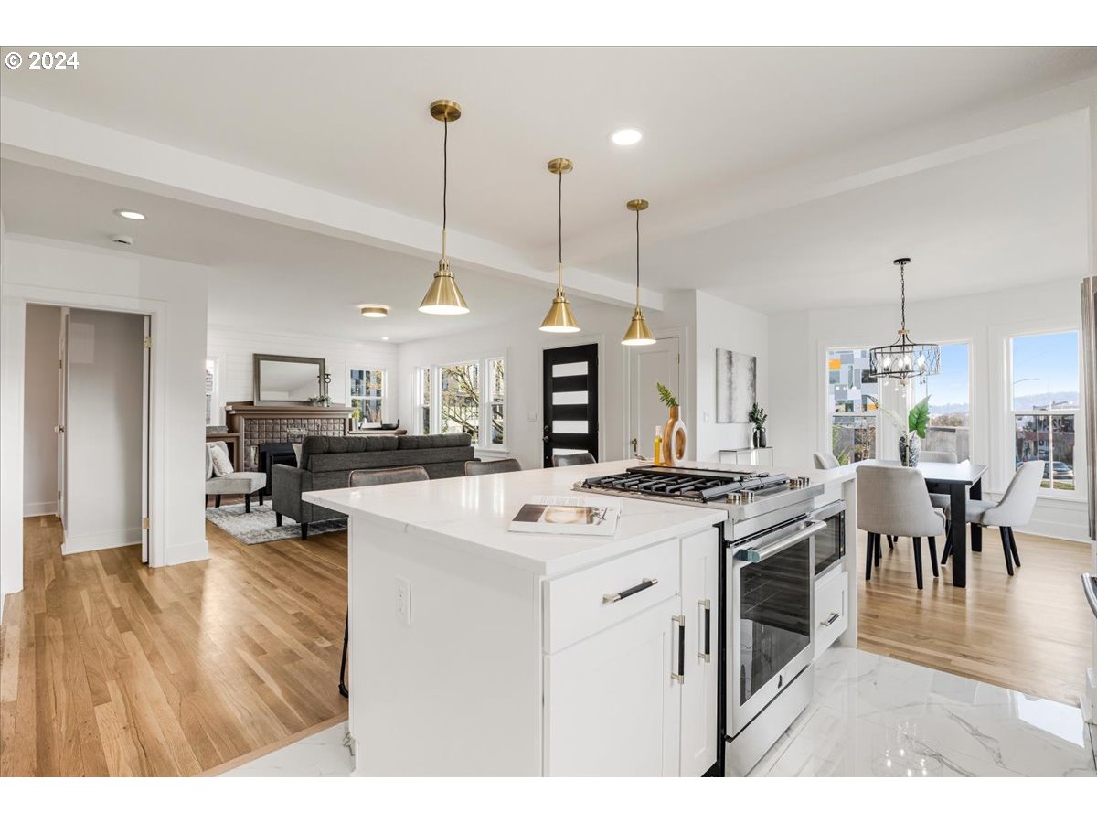 2639 North Sumner Street Portland, OR 97217 - Photo 9 of 46 a open kitchen with stainless steel appliances kitchen island a stove a refrigerator a oven a sink with a dining table and chairs