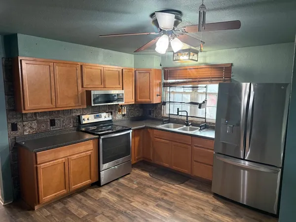 a kitchen with stainless steel appliances granite countertop a refrigerator a stove a sink and a microwave