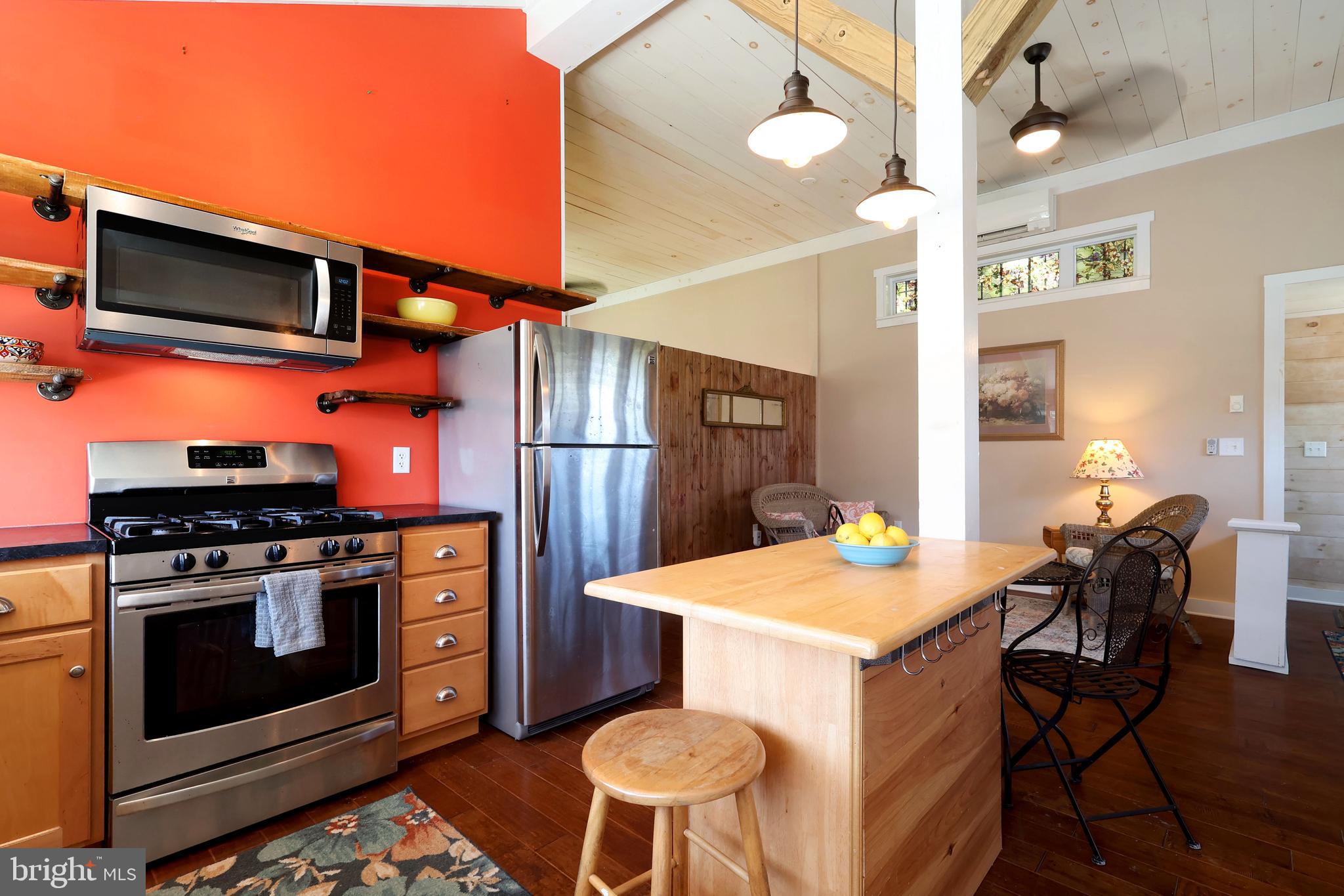 1343 Penns Creek Road Coburn, PA 16832 - Photo 53 of 92 a kitchen with stainless steel appliances kitchen island granite countertop a stove a refrigerator a dining table and chairs with wooden floor