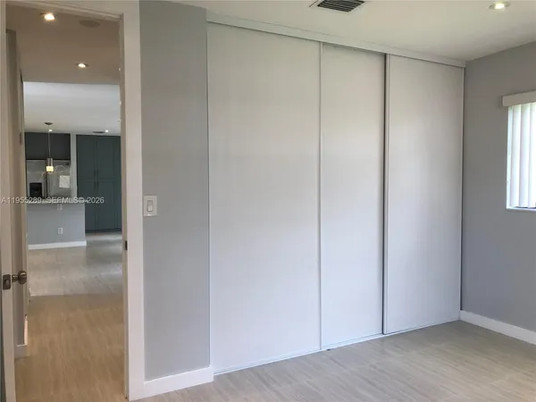 a view of a hallway with wooden floor and a bathroom
