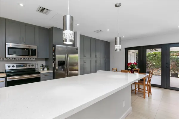 a kitchen with stainless steel appliances a dining table chairs refrigerator and sink