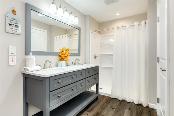 a bathroom with a granite countertop sink a mirror and a shower