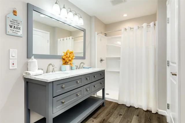 a bathroom with a granite countertop sink a mirror and a shower