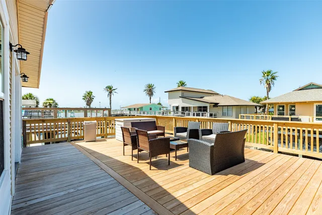 a view of a roof deck with table and chairs couches with wooden floor and fence
