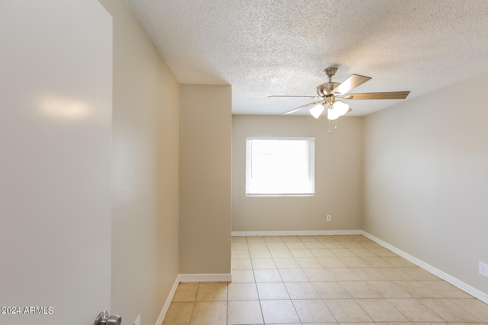 6963 West Pierson Street Phoenix, AZ 85033 - Photo 10 of 21 an empty room with a chandelier fan and windows