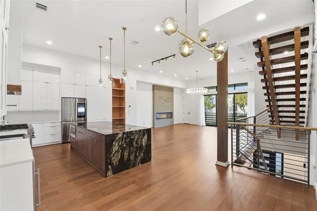a living room with couches and kitchen view with wooden floor