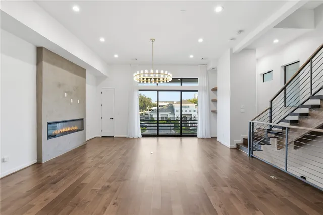 a view of an empty room with wooden floor entryway and a window