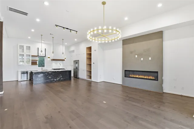 a view of a kitchen with a stove kitchen island wooden floor and a chandelier