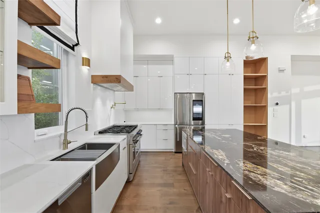 a kitchen with stainless steel appliances granite countertop a sink a stove and refrigerator