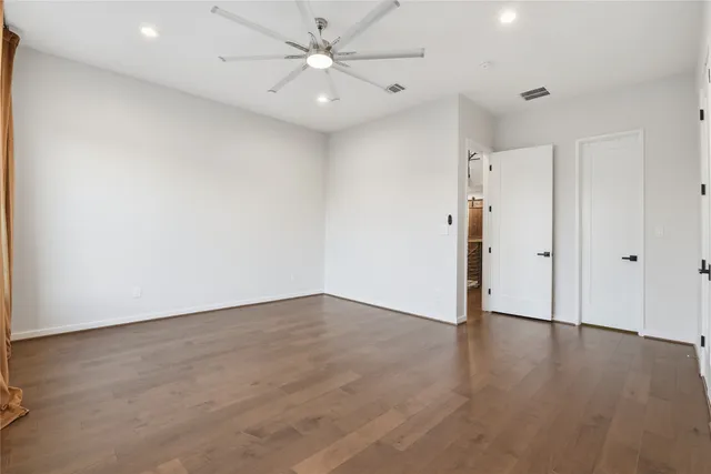 an empty room with wooden floor and ceiling fan