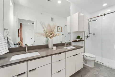 a bathroom with a double vanity sink toilet and shower