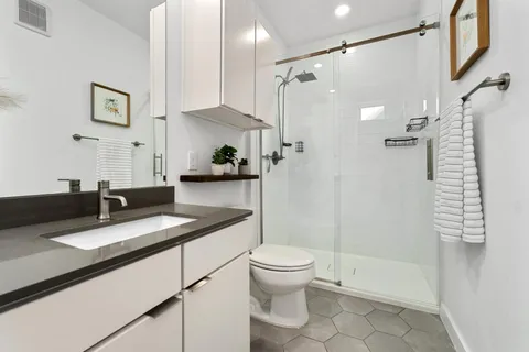 a bathroom with a granite countertop sink toilet and shower
