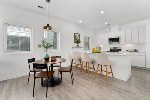 a kitchen with stainless steel appliances granite countertop a stove a sink a microwave a dining table and chairs with wooden floor