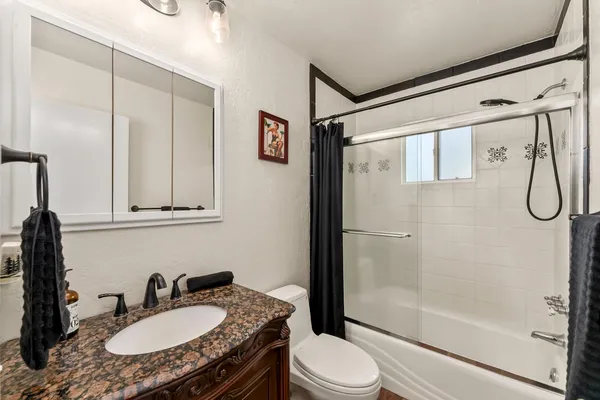 a bathroom with a granite countertop sink toilet a mirror a vanity and shower