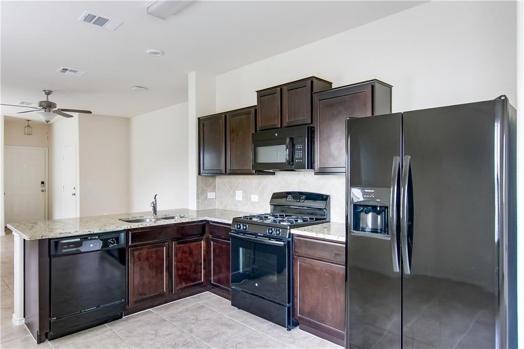 5916 Kennedy Street Austin, TX 78747 - Photo 1 of 25 Kitchen with black appliances, dark wood finish cabinets, a peninsula, light stone countertops, and a ceiling fan